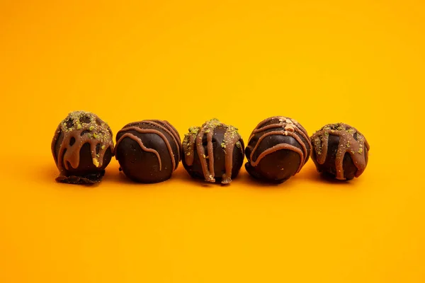 Runde Dunkle Pralinen Mit Nüssen Und Pistazien Isoliert Auf Gelbem — Stockfoto