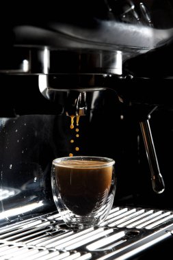 Koyu kahve damlaları şeffaf cam bir espresso bardağına damlıyor. Elle yapılan espresso makinesinde fotokopi alanı var.