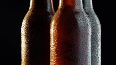 Siyah arka planda dönen üç bira şişesi.