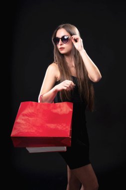 Siyah arka planda alışveriş çantası olan zarif ve güzel bir kadın.