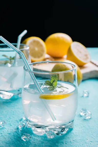 Limonların yanında bir bardak limonata, mavi arka plan.