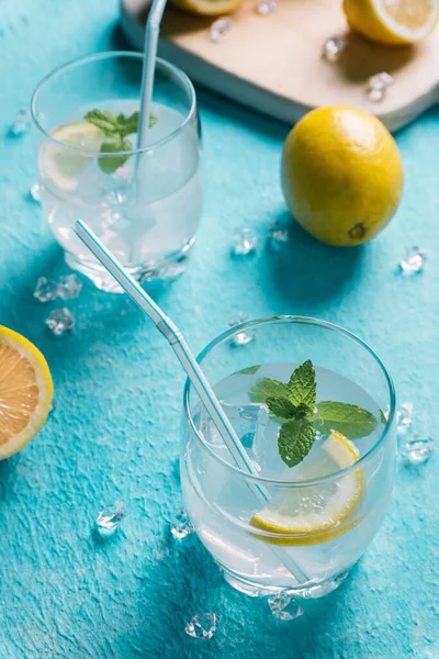 Limonların yanında bir bardak limonata, mavi arka plan.