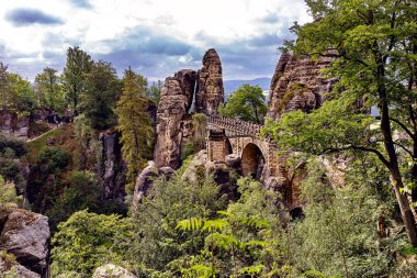 Bastei, Bastei köprüsü ve taş kapı manzaralı. Bastei, Dresden yakınlarındaki Sakson İsviçre Ulusal Parkı 'ndaki güzel kaya oluşumuyla ünlüdür. Saksonya 'da popüler seyahat noktası