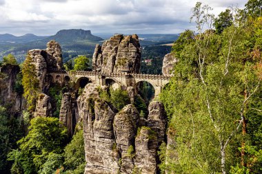Bastei, Bastei köprüsü ve taş kapı manzaralı. Bastei, Dresden yakınlarındaki Sakson İsviçre Ulusal Parkı 'ndaki güzel kaya oluşumuyla ünlüdür. Saksonya 'da popüler seyahat noktası.