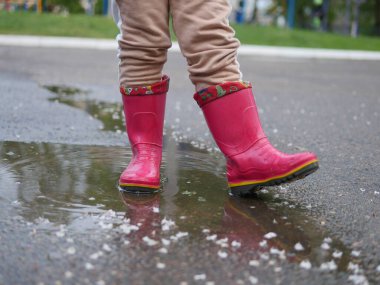 Lastik botlar içindeki çocukların bacakları su birikintisindedir. pembe çocuklar lastik botlar