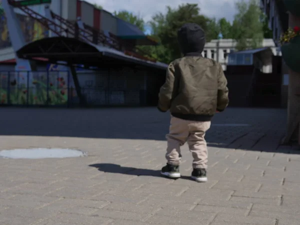 Küçük oğlan yalnız gidiyor. Arkadan bak. Bebek yalnız, ailesi yok.