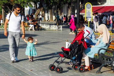 Istanbul, Türkiye - 21 Ağustos 2018: küçük bir kız elini Sultanahmet'te kare bir bankta oturan evli bir çift için dalgalar bir kız ile bir adam girer