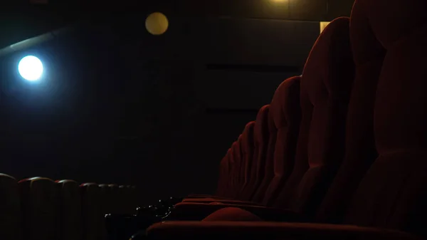 Red chairs in cinema in dark, lit lantern. Selective focus