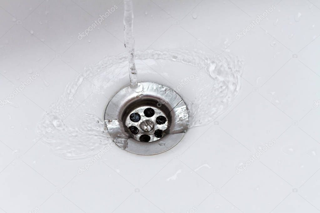 water flowing from faucet into sink drain