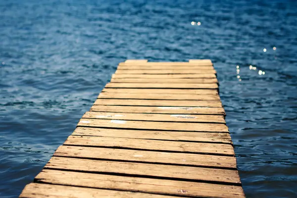 Wooden pier on background of blue water, selective focus — Stock Photo, Image