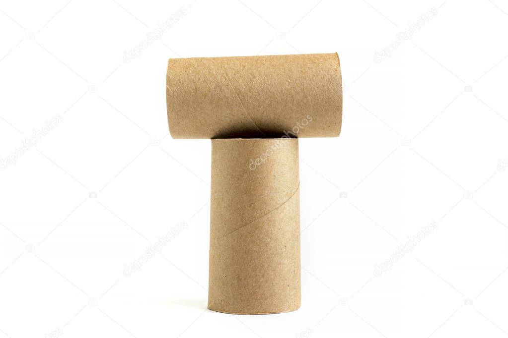 Letter T from composition of two cardboard paper tubes on white background. Close-up of empty toilet rolls