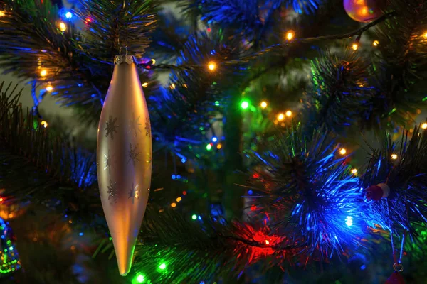 Brinquedo na forma de um gelo paira sobre uma árvore de Natal com guirlandas. Espaço de cópia, foco seletivo — Fotografia de Stock