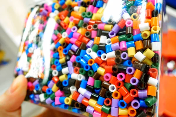 Assorted colors of Ikea Pyssla thermo-mosaic beads in a transparent container, selective focus — Stock Photo, Image