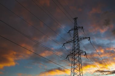 Dramatik renkli gökyüzünün arka planında iletim güç kulesi. Kafes kulesi, bir elektrik hattını desteklemek için kullanılır.