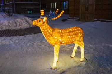 Ren geyiği Noel süslemesi aydınlatılmış, ışıklandırılmış Akrilik geyik figürü kış kenti parkında.