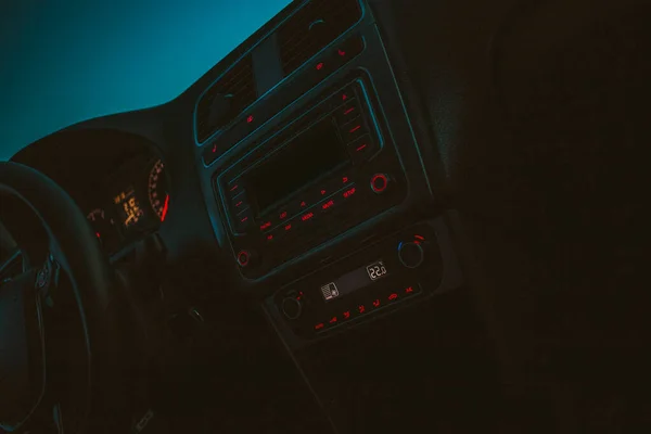 dashboard, interior of the car, climate control is displayed on the control panel of the car audio system, display 20 degrees,black buttons with red lights, through the window you can see the blue sky