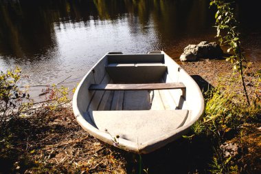 sakin göl kıyısındaki eski bir balıkçı teknesi su kıyısında duruyor cheloaek kıyıya çıktı ve botu yerde bıraktı yeşil çalıların ve ağaçların arasında yüzemiyordu