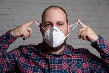 KN-95 koruma maskesi takan genç bir adam. Virüs ve salgın hastalığın yayılmasını önlemek için koruyucu ağız filtresi maskesi. Hastalıklar, grip, hava kirliliği, corona virüsü konsepti