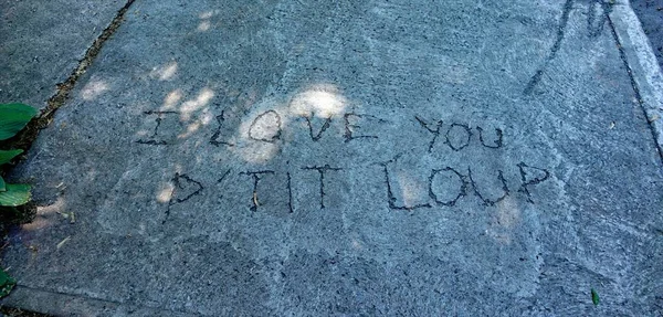 english - french message / text scratched on the ground asphalt / concrete \