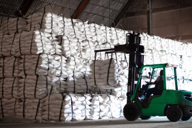Forklift şeker torbasını deponun içine istiflemek, şeker deposu operasyonu. İthalat ve ihracat için tarım ürünü depolama ve lojistik.