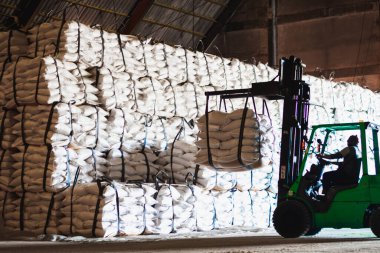Forklift şeker torbasını deponun içine istiflemek, şeker deposu operasyonu. İthalat ve ihracat için tarım ürünü depolama ve lojistik.