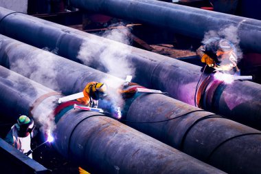 Koruyucu maskeli işçiler inşaat alanında metal kaplama taşıyordu.