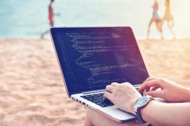 Plajda rahat bir çalışma ortamında kaynak kodlar yazan bir programcı. Öğrenim, Çalışma, Teknoloji, Serbest Çalışma Konsepti.