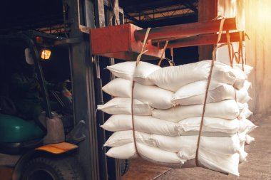 Forklift beyaz şeker torbasını depodan ihracat için konteynıra doldurmak için kullanıyor..