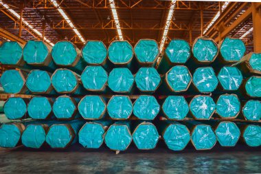 Büyük bir dağıtım deposunun içindeki katmanlara yerleştirilmiş çelik tüp yığınları. Çelik depo lojistik operasyonları.