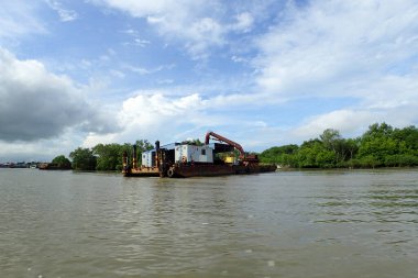 Güneşli bir günde bulutlu mavi gökyüzünün altında yavaş nehir boyunca balıkçı teknesi