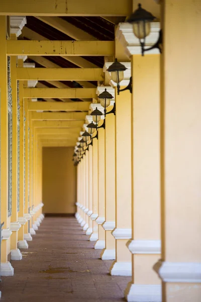 Colonial corridor architecture design with columns painted in yellow with electrical lightings