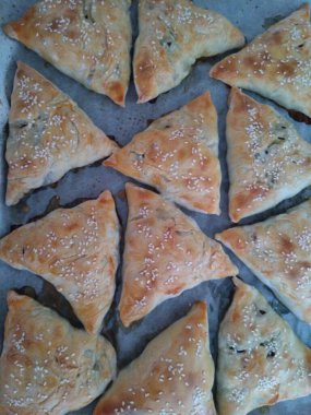 Üçgen etli turta pişirme işlemi, üzerine puf böreği serpiştirilmiş susam serpiştirme. Samsa-bir tabak Özbek mutfağı