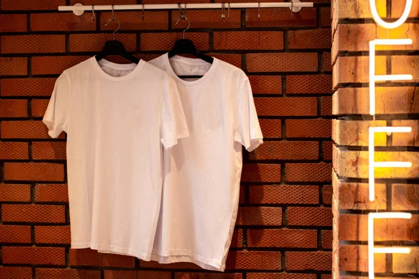 White T-shirts hang on hangers. For a clothing brand.