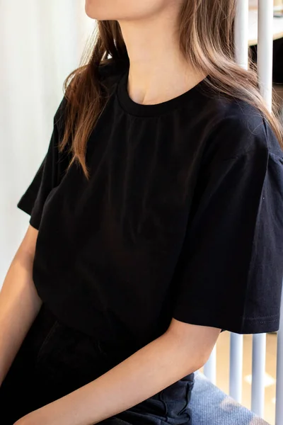 Siyah tişörtlü ve siyah etekli genç bir kadın. Bir giyim markası için. Model.