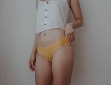 Sarı iç çamaşırlı kadın kalçaları ve midesi.