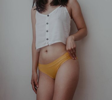 Sarı iç çamaşırlı kadın kalçaları ve midesi.