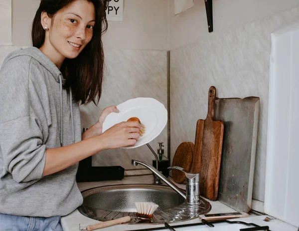 食器洗い機を使わずに皿を洗う女性 — ストック写真