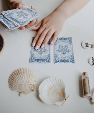 : Elinde tarot kartları tutan bir kadın.