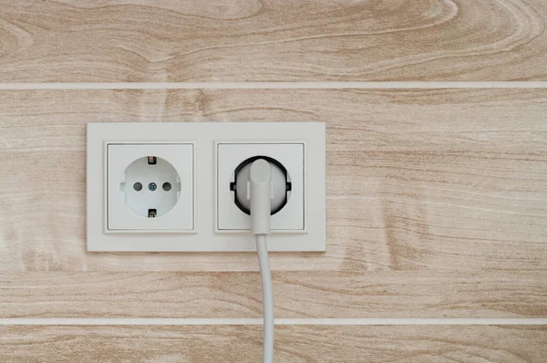 White electric power sockets on wall background with plugged electric plug.