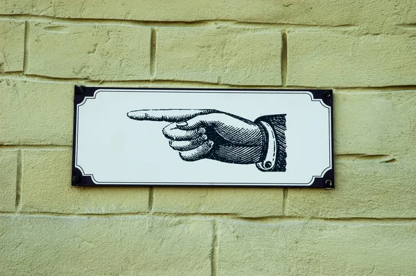 Graphic old-style pointer with hand in black and white shading on a wall