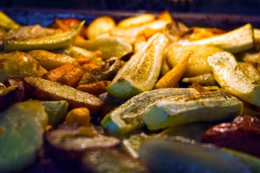 Fırında pişirilmiş rezene, sebze iliği, kabak, havuç ve kabuklu patatesler mavi ışıkta yakın plan görüntüsü.