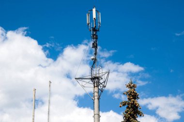 Telekomünikasyon televizyon antenleri. Telekomünikasyon GSM alımı ve iletimi. Telefon direği uydu 4G kulesi. Cep telefonu anteni, mavi gökyüzünde bulutlar olan telekomünikasyon kulesi.