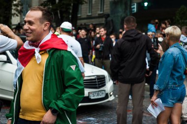 KYIV, UKRAINE - 13 AĞUSTOS 2020: Belarus 'ta Beyaz Rusya Büyükelçiliği yakınlarındaki protestolara destek veren omuzlarında Belarus bayrağı taşıyan genç adam, Beyaz Rusya Büyükelçiliği yakınlarındaki protestocular, şiddet karşıtı afiş taşıyan protestocular