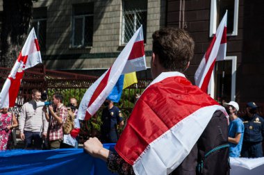 KYIV, UKRAINE - 16 AĞUSTOS 2020: Belarus 'ta Beyaz Rusya Büyükelçiliği yakınlarındaki protestoları destekleyen omuzlarında Beyaz Rusya bayrağı olan genç adam, Beyaz Rusya Büyükelçiliği yakınlarındaki protestocular