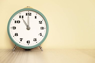 Saat 11: 00 'e ayarlanmış antika analog saat. Saat 23: 00. Çalar saat masanın üstünde.
