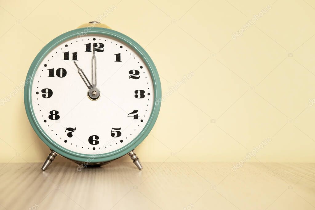 Antique analog clock with hands set at 11:00. 23:00 The alarm clock is on the table