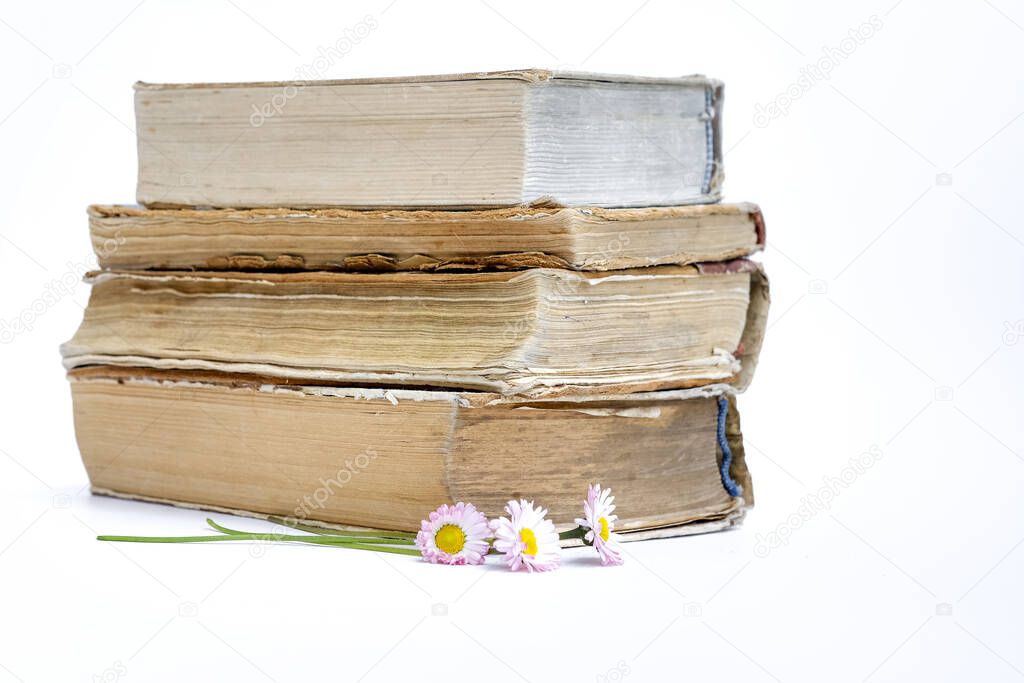 a stack of old books. bouquet of flowers from daisies on a white background