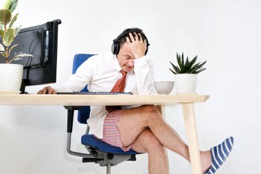 Erkek müdür evde uzaktan çalışıyor, online toplantılar yapıyor. O yorgun ve utangaç. O bir gömlek ve kravat, iç çamaşırı ve terlik giyiyor. Evde kal ve karantinaya al..