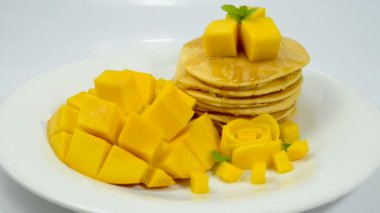 Mango ile krep ve bal şurubu. Tatlı, lezzetli, popüler yaz yemeği. Taze mango çiçeği şeklindeki yan görünüm.