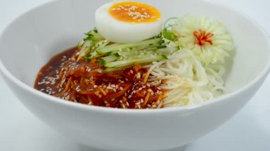 Kore Baharatlı Erişte Guksu, Beyaz Kase 'de Kaynamış Yumurta Geleneksel Kore Yemeği Popüler Yemek Dekorasyonu Pırasalı çiçek şekli